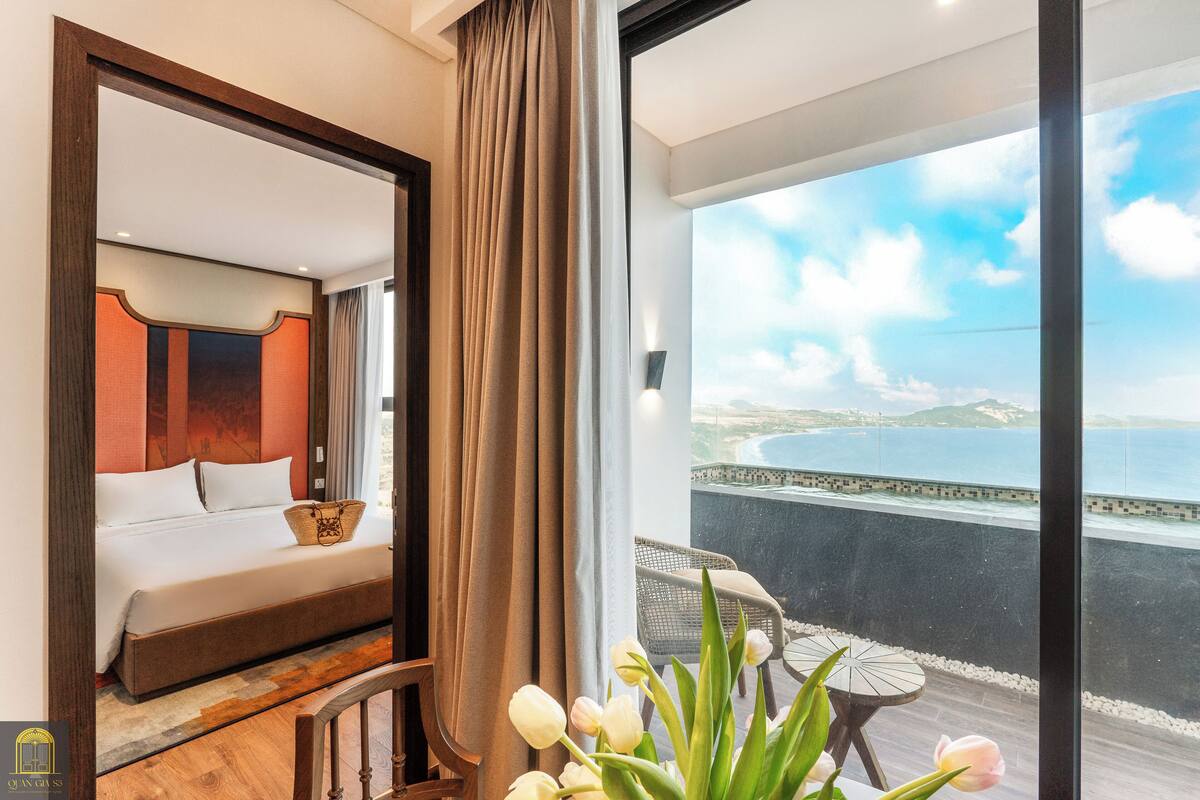 Une chambre avec une grande fenêtre, un lit, une chaise et une vue sur la mer.