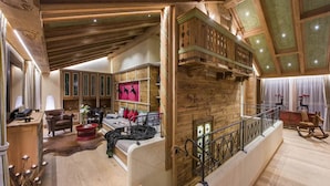 Ein geräumiges Wohnzimmer mit hohen Decken, Holzbalken und einer Treppe mit Geländer.