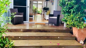 Un escalier en bois mène à un espace de vie aménagé avec des meubles en osier et un téléviseur.
