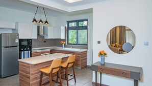 Eine moderne Küche mit einer zentralen Kochinsel, Barhocker, einem eingebauten Ofen und einem großen Fenster.