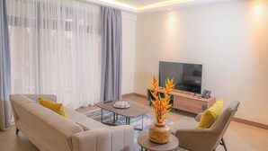 Ein modernes Wohnzimmer mit einer Couch, Sesseln, einem Couchtisch und einem Fernseher.