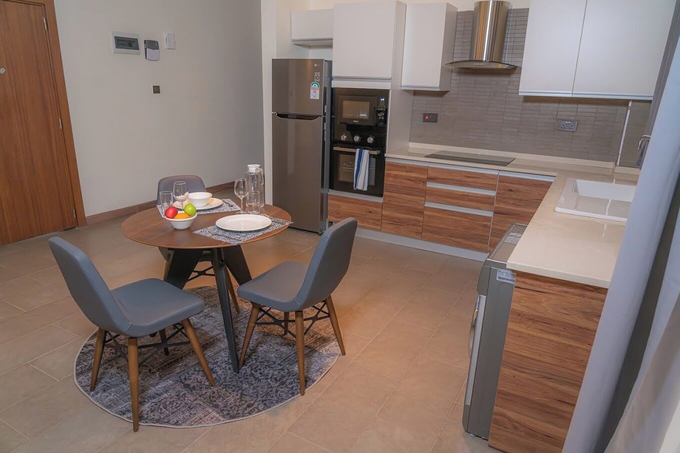 Una cucina moderna con zona pranzo, dotata di frigorifero, forno, microonde e mobili in legno.