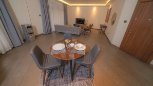 Ein modernes Wohnzimmer mit Essbereich, einer Couch, einem Fernseher und einer Holztür.