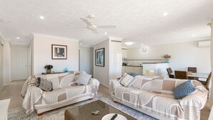A modern living room with two sofas, a coffee table, and a dining area with a table and chairs.
