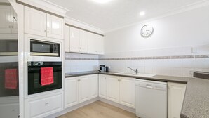 A modern kitchen with white cabinets, a microwave, oven, and dishwasher.
