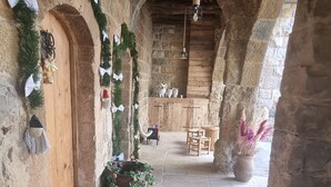 A stone corridor with wooden doors, festive garlands, and a rustic interior.