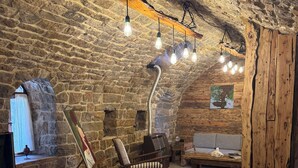 A rustic room with a stone wall, a wooden bed, a chair, and a sofa.