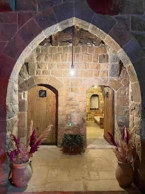 An arched stone doorway leading to a room with a wooden door and a small plant in the center. - Bayt Wadad, Bcharre Lebanon (Bsharri)