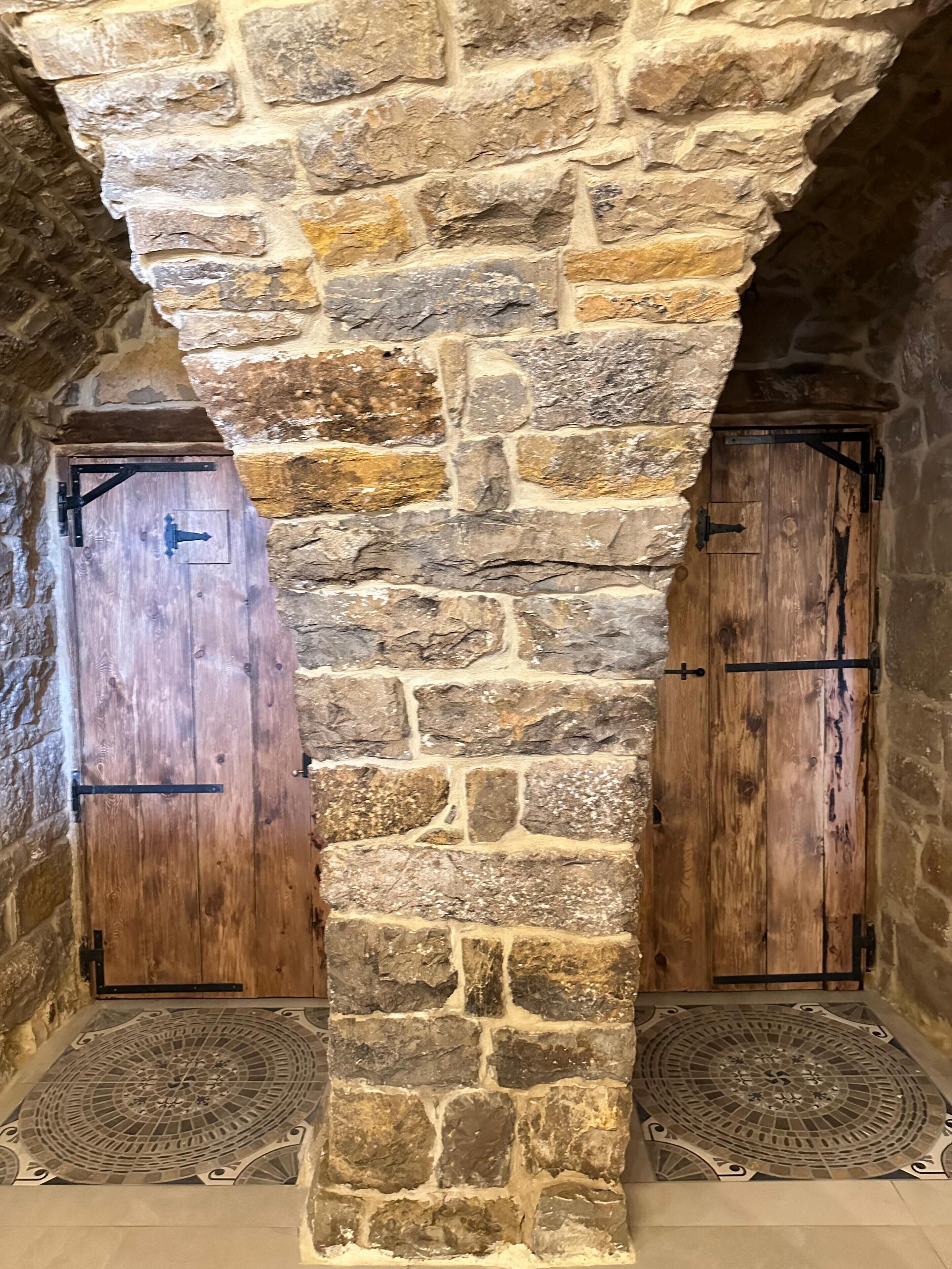 Un arco de piedra con dos puertas de madera, cada una con un cerrojo de metal.