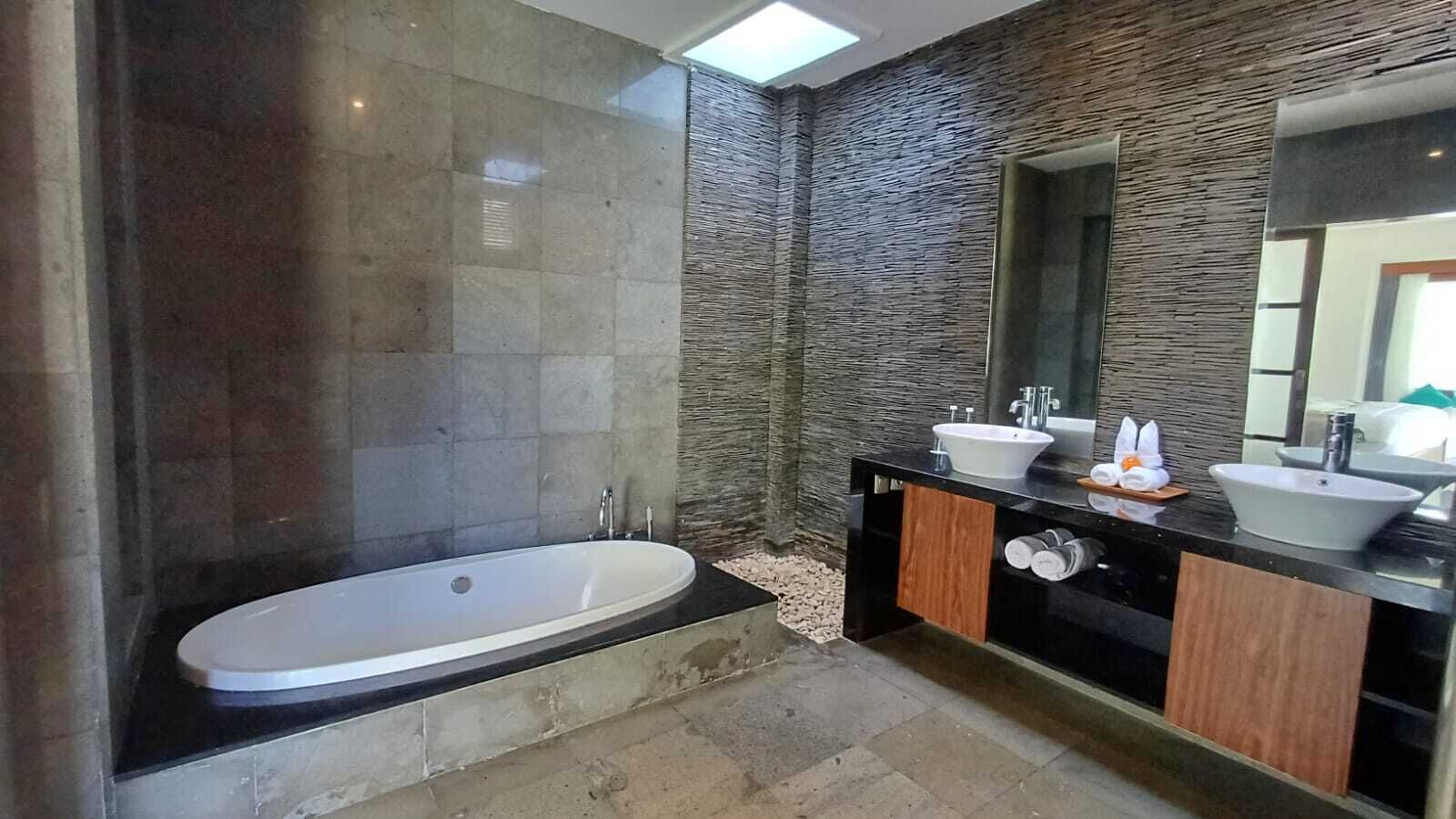 A modern bathroom with a freestanding bathtub, two sinks, and a large mirror.