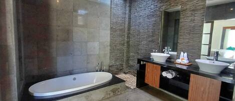 A modern bathroom with a freestanding bathtub, two sinks, and a large mirror.