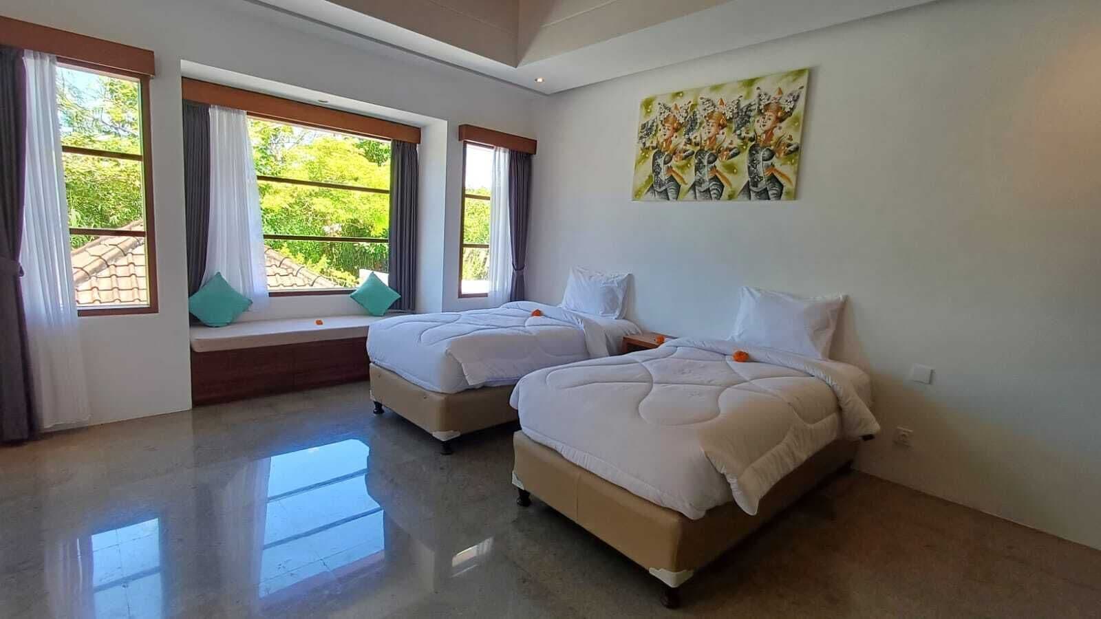 A hotel room with two beds, large windows, a balcony, and a painting on the wall.