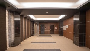 A modern hallway with a skylight, elevators, and a tiled floor.