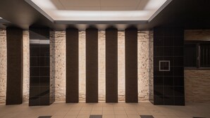 A lobby with stone columns, a reception desk, and a tiled floor.