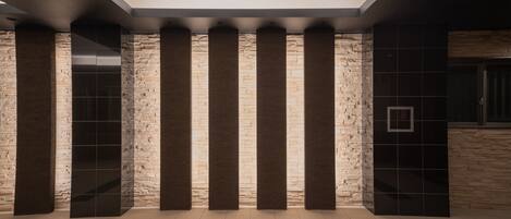 A lobby with stone columns, a reception desk, and a tiled floor.