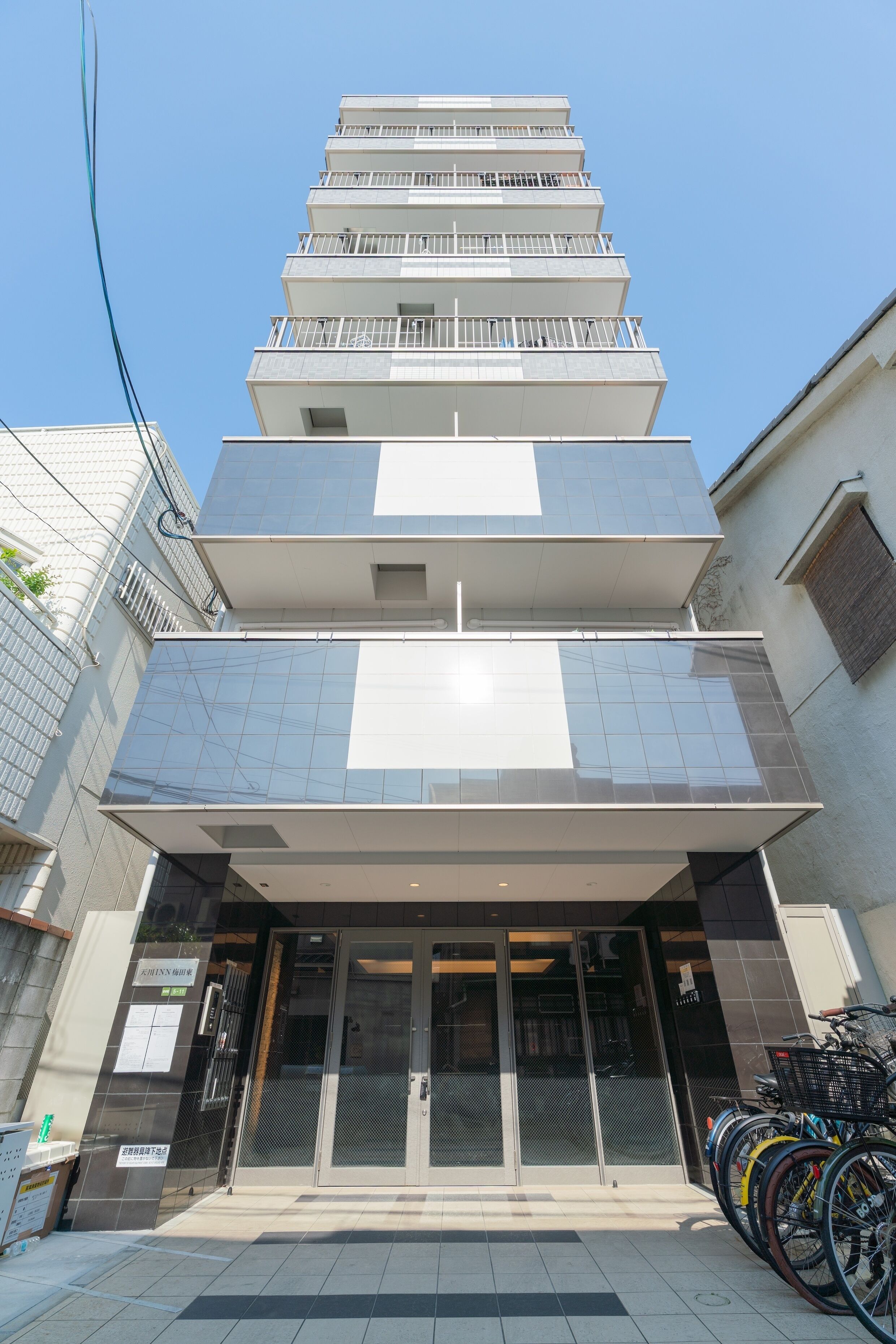 A multi-story building with a modern design, featuring a glass facade and a series of balconies.