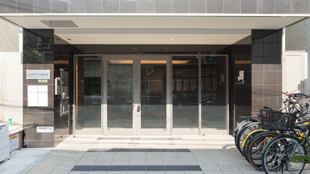 A modern building entrance with glass doors and a bike parking area.