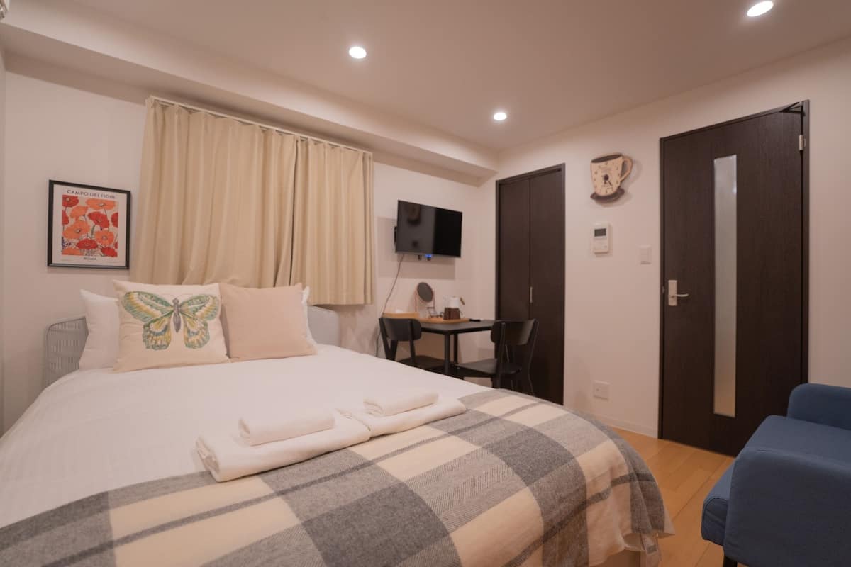 Une chambre bien rangée, avec un lit, un bureau et un téléviseur.