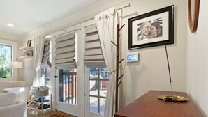 Een woonkamer met een bank, een salontafel, een deur met uitzicht en een lijst met een afbeelding aan de muur.