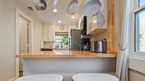 Een moderne keuken met een houten aanrecht, twee barkrukken en verlichting boven.