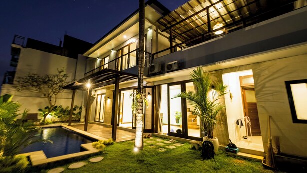 A modern two-story house with a swimming pool, large windows, and a covered patio area. - Casa Purnama Villa (Sukawati)