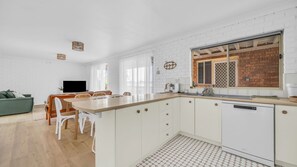 Eine moderne Küche mit weißen Schränken, einer Holzauskładung und einem eingebauten Geschirrspüler.