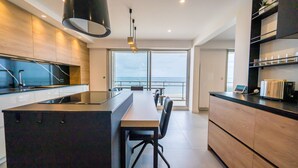 Une cuisine moderne dotée d’un grand îlot central, d’appareils électroménagers intégrés et offrant une vue sur l’extérieur.