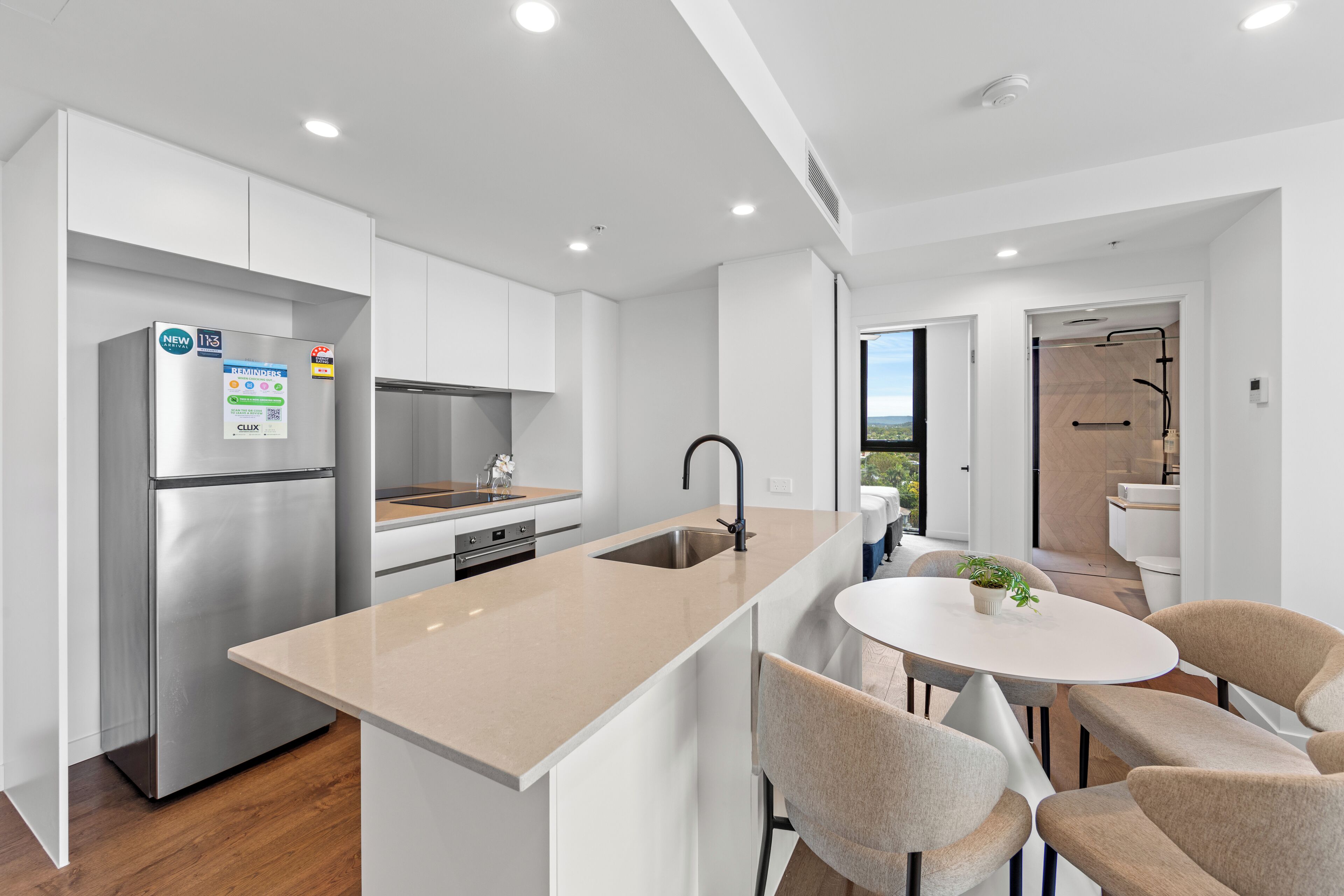 Una cocina moderna con un refrigerador de acero inoxidable, un lavamanos y una zona de comedor con una mesa redonda y sillas.