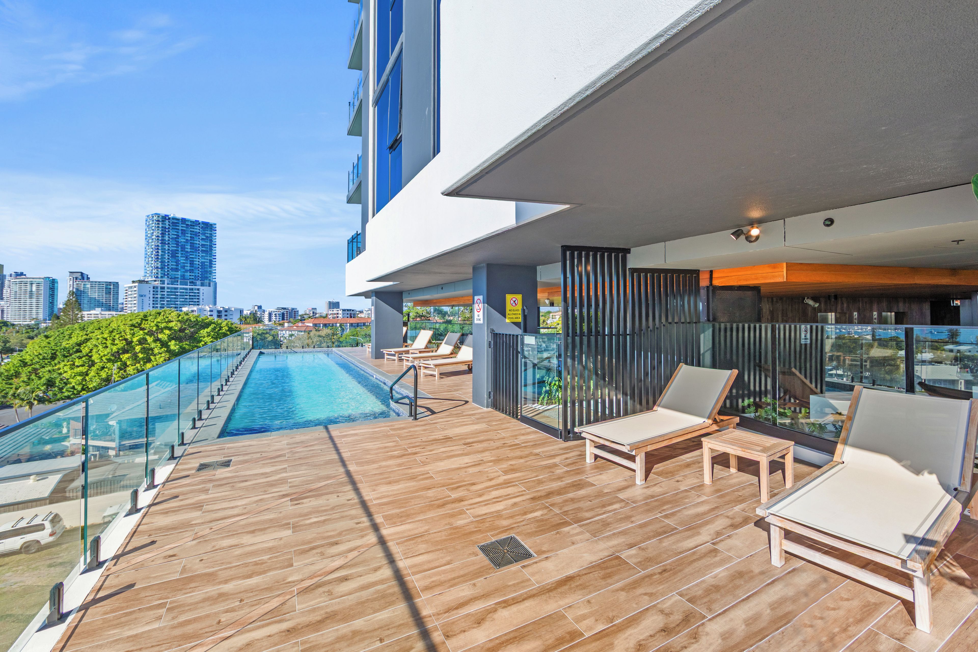 A modern outdoor pool area with lounge chairs and a glass railing.