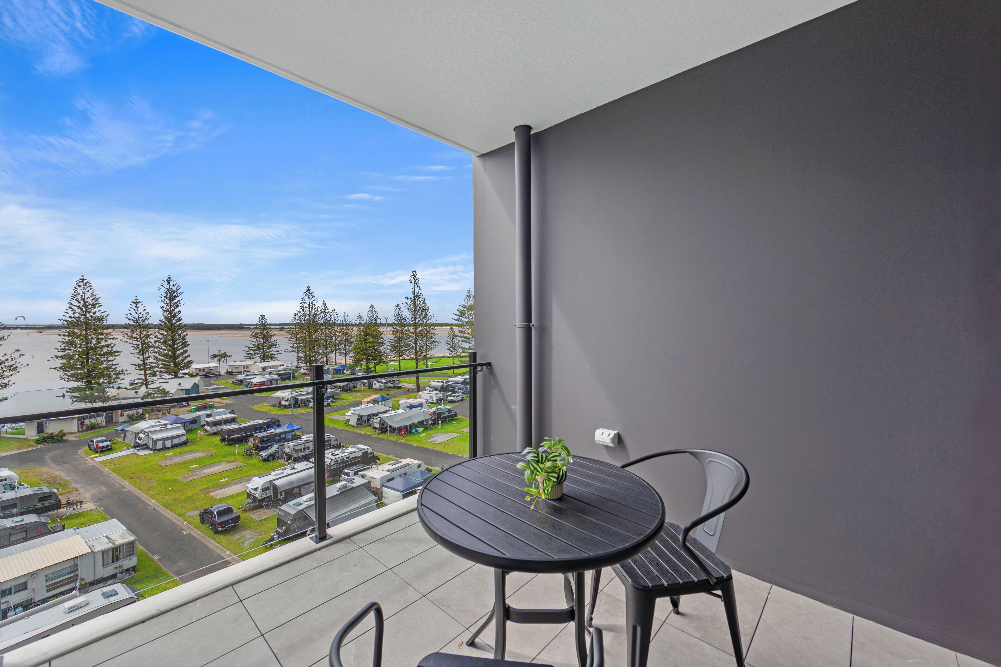 A balcony with a view of a parking area and a body of water.