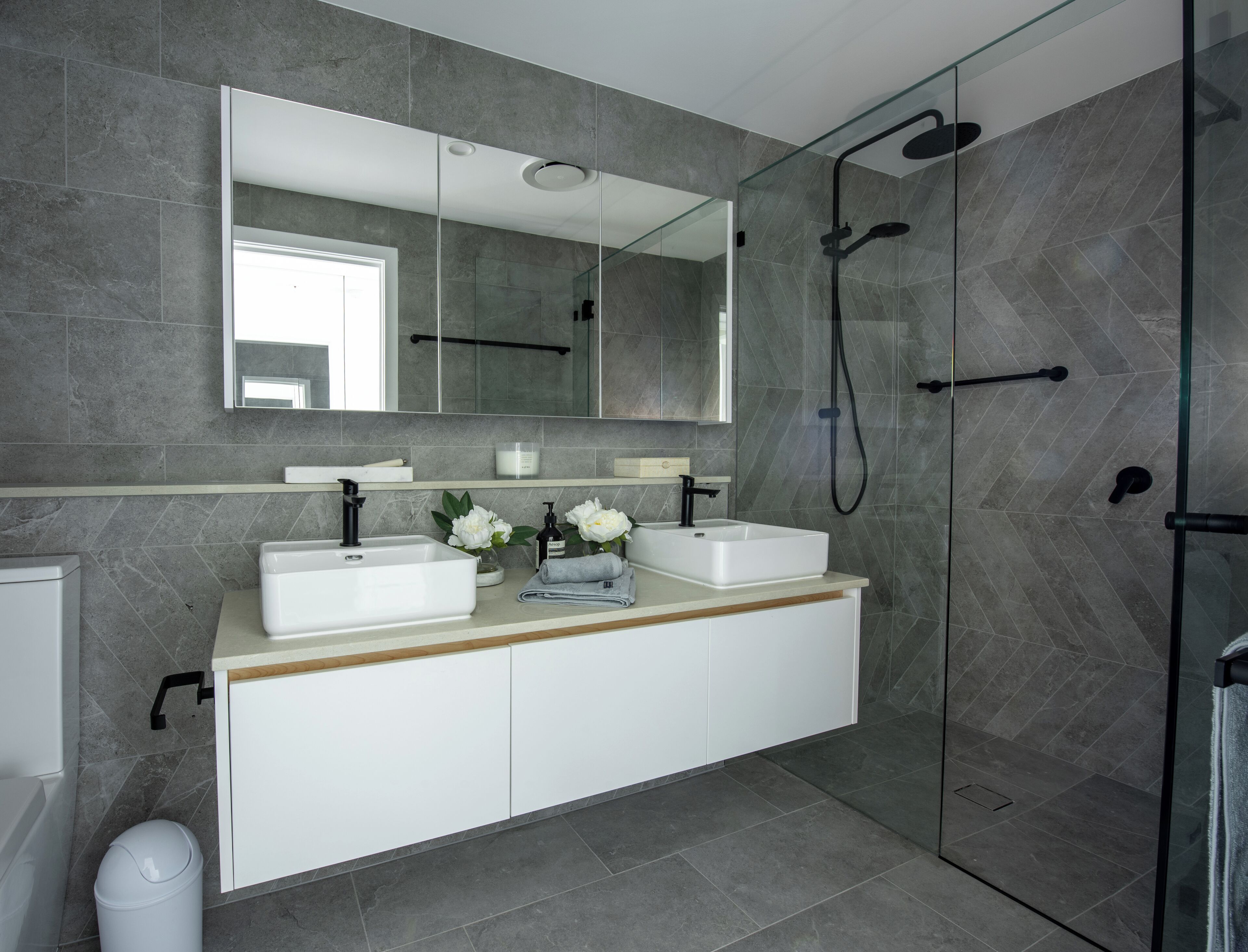 Une salle de bain moderne avec deux lavabos, un grand miroir et une douche à l’italienne.