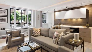 Una sala de estar moderna con un sofá, una mesa de centro y una zona de cocina con un ventanal grande.