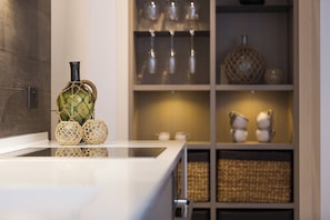 Modern kitchen with sleek countertop, decorative vases, and minimalist shelving unit.