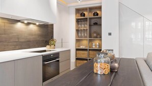 Una cocina moderna con electrodomésticos integrados, un comedor con mesa de madera y una sala de estar con sofá.