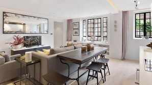 Una sala moderna con un sofá grande, una mesa de comedor y una cocina con ventana.