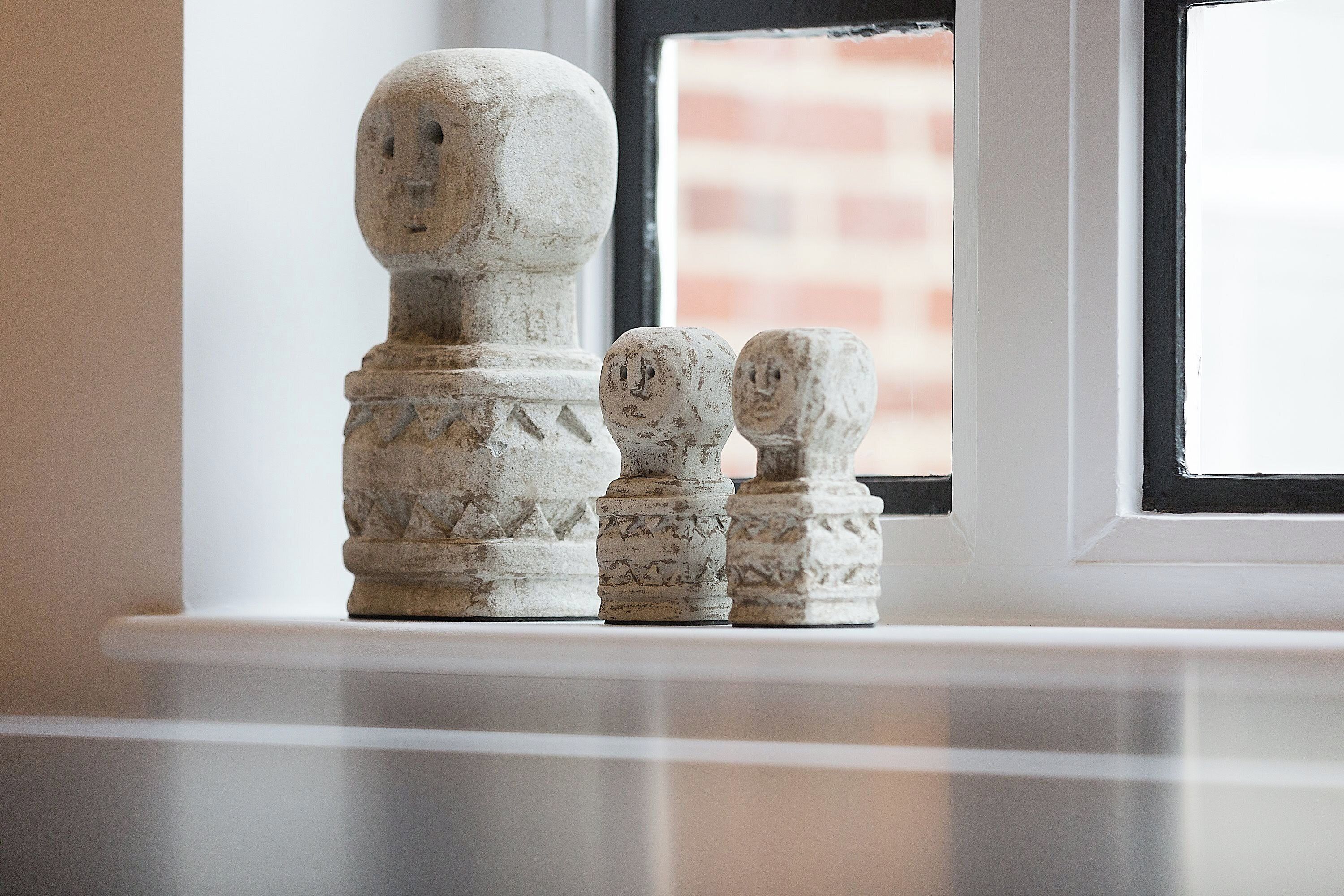 A set of stone candle holders on a windowsill.