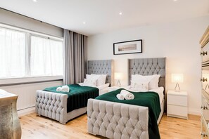 Habitación de hotel con dos camas, una mesita de noche, una lámpara y un cuadro en la pared.