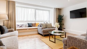 A modern living room with a sofa set, a coffee table, and a TV mounted on the wall. - 4 Bedroom Villa on Marble Arch (London)