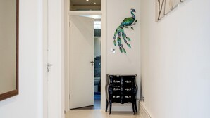 A hallway with a black cabinet, a peacock wall decoration, and a door leading to another room. - 4 Bedroom Villa on Marble Arch (London)