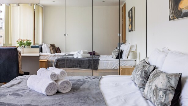 A hotel room with two beds, a desk, and a chair. There are towels on the beds and a plant on the desk. - Penthouse With Views Across London (London)