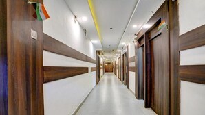 A long, narrow hallway with wooden paneling and doors on both sides. - Diamond By Glitz Hotels (Mumbai)