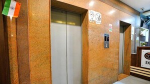 An elevator with a control panel, a sign with symbols, and a flag. - Diamond By Glitz Hotels (Mumbai)