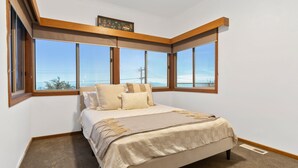 Ein Schlafzimmer mit einem großen Bett, mehreren Fenstern und Meerblick.