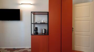 Una habitación con un armario rojo, un televisor de pantalla plana en la pared y una puerta con interruptor de luz.