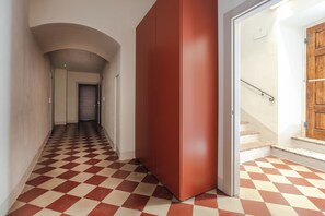 A hallway with a checkered floor, a red cabinet, and a wooden door at the end. - AmiRooms Affittacamere (Siena)
