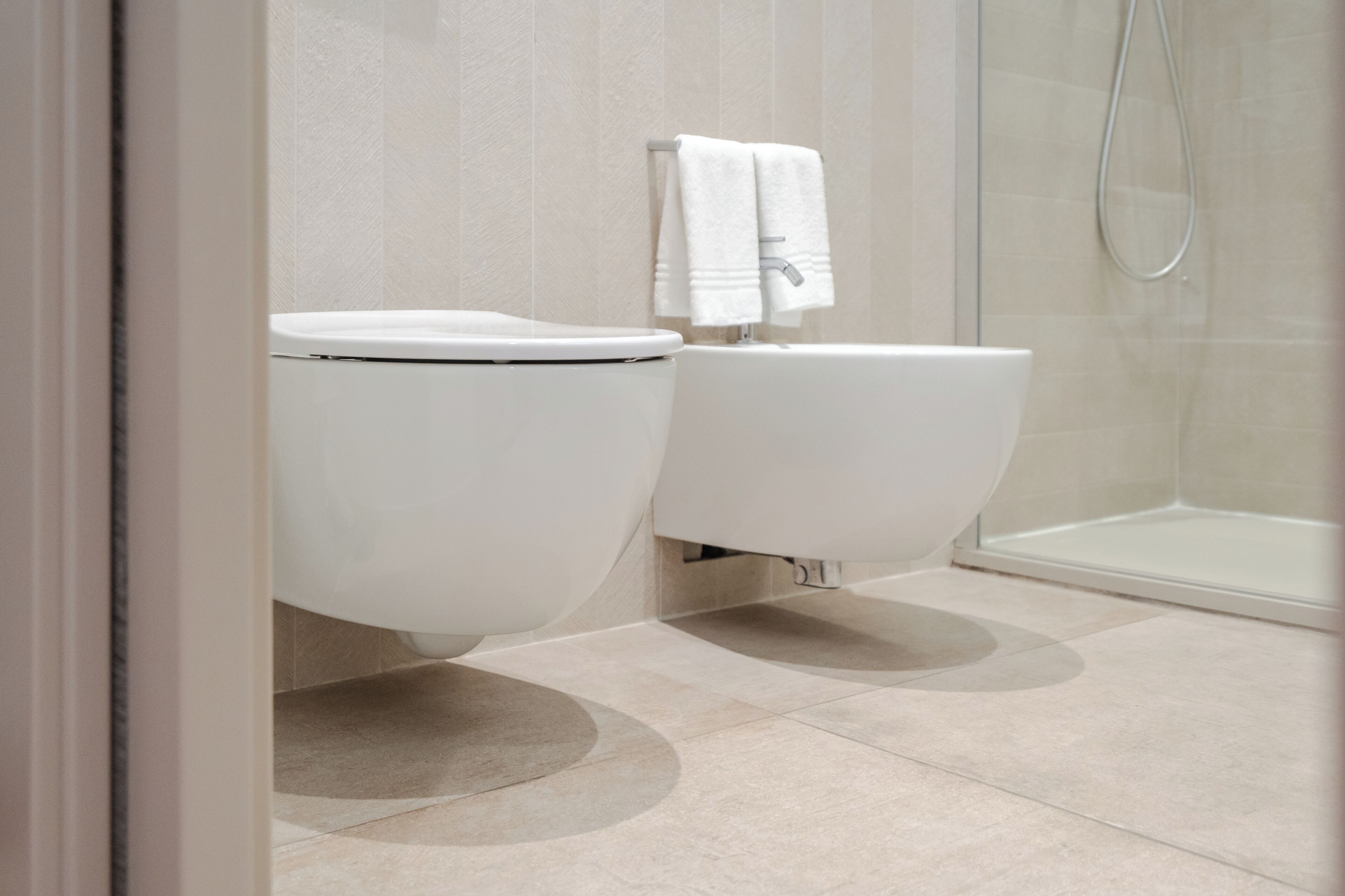 Et moderne badeværelse med toilet, bruser og håndklædetørre.