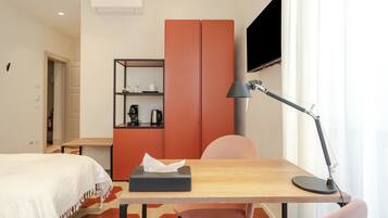 A hotel room with a bed, a desk with a lamp, a wardrobe, and a television.