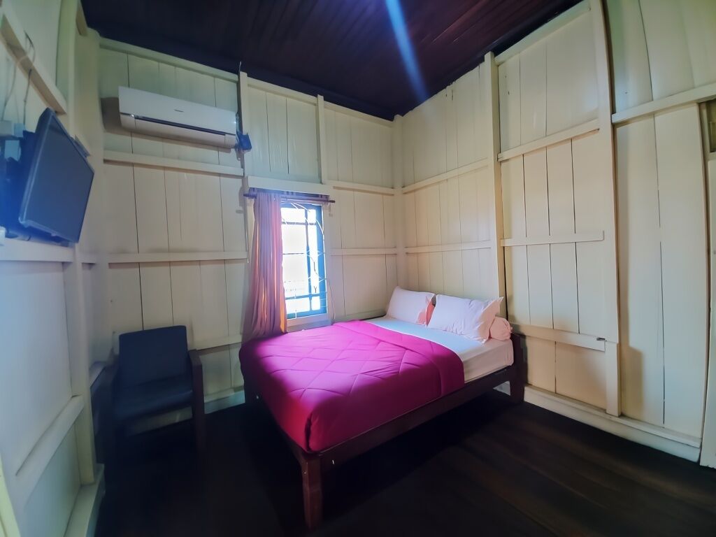 A room with a bed, a chair, and an air conditioning unit.