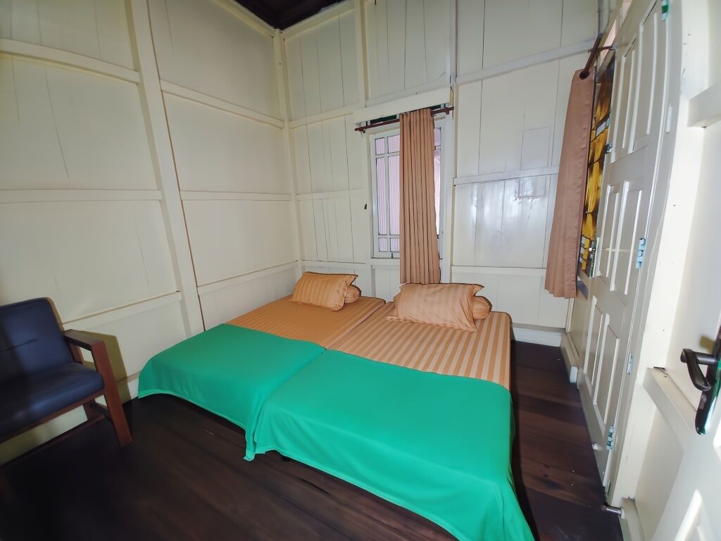 A room with two beds, a chair, and a window with curtains.