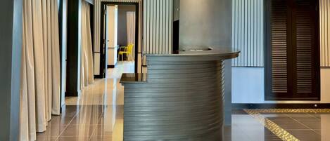 A modern reception area with a curved counter, a chair, and a door with vertical blinds.